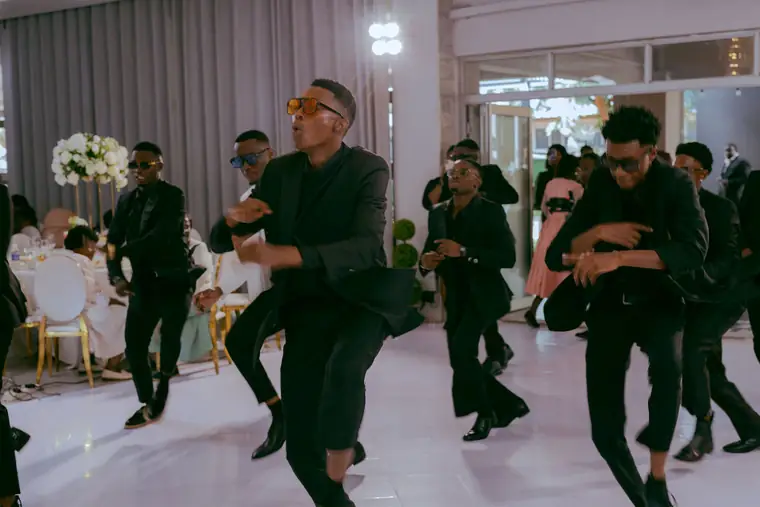 Groomsmen in black leaping in a choreographed routine