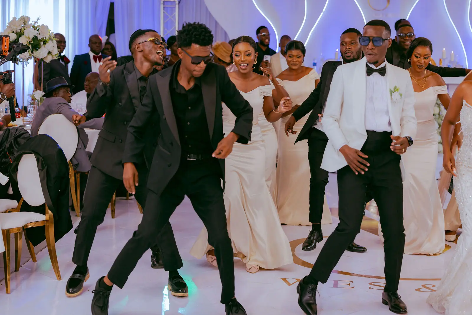 A dance crew in black performing with the bride and groom