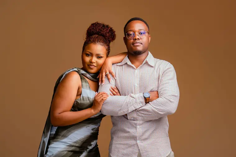 A couple posing arms folded against a caramel backdrop