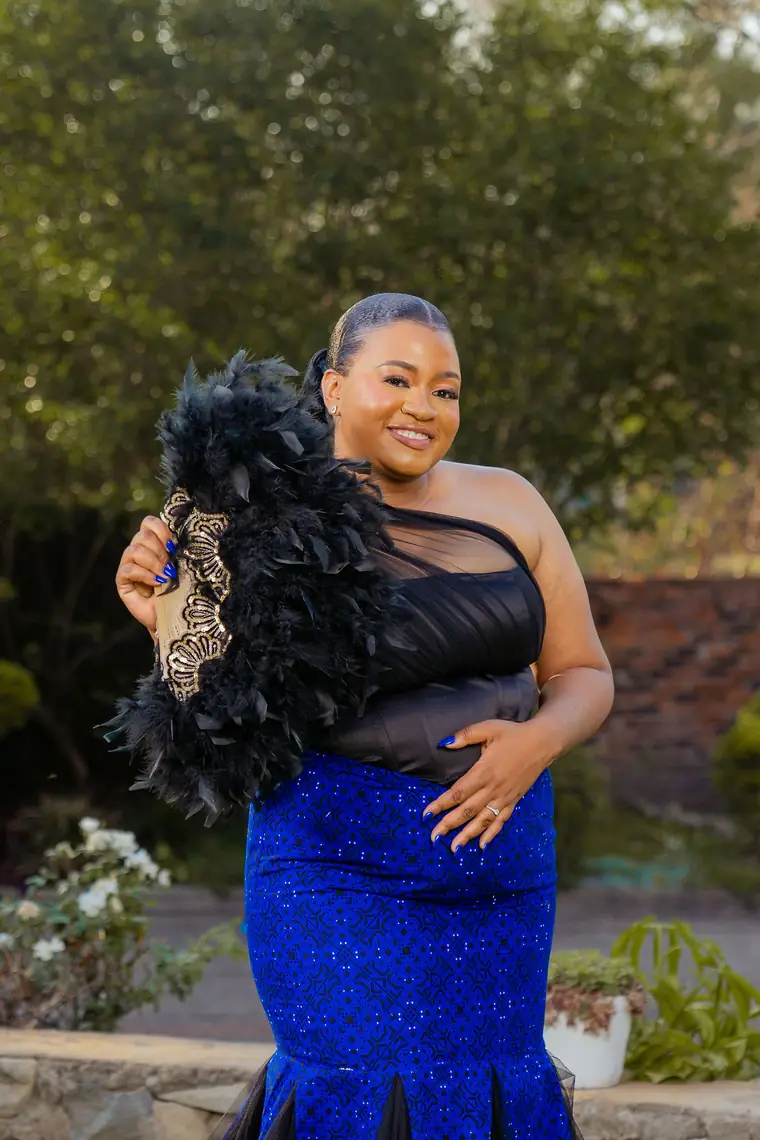 A bride in royal blue holding a black feather fan
