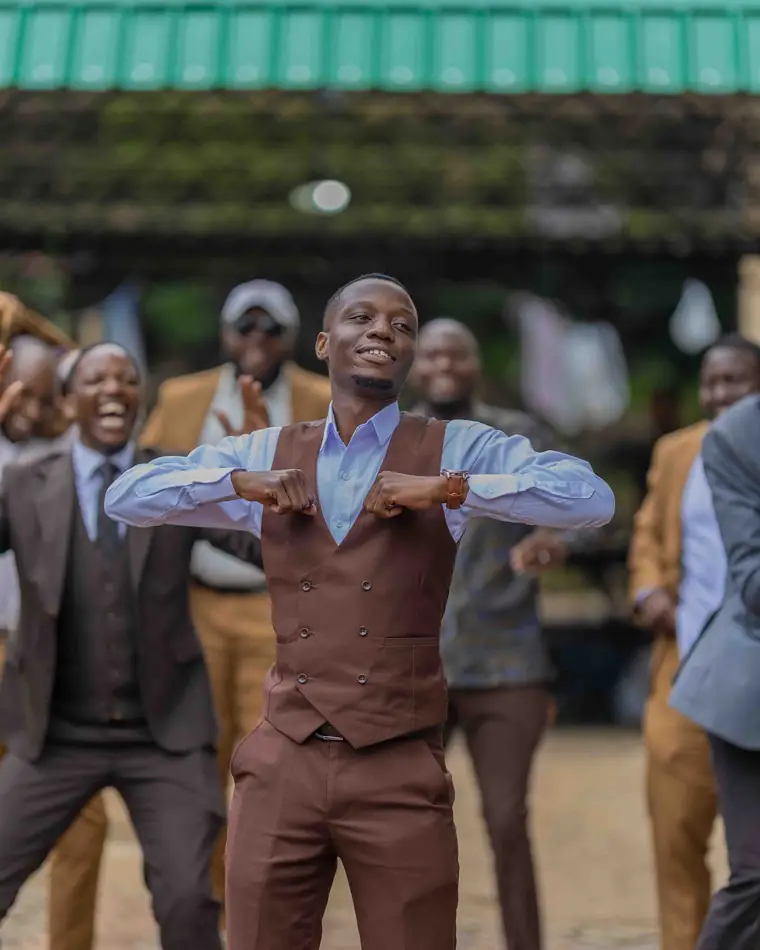 A groom in a brown suit dancing with his crowd