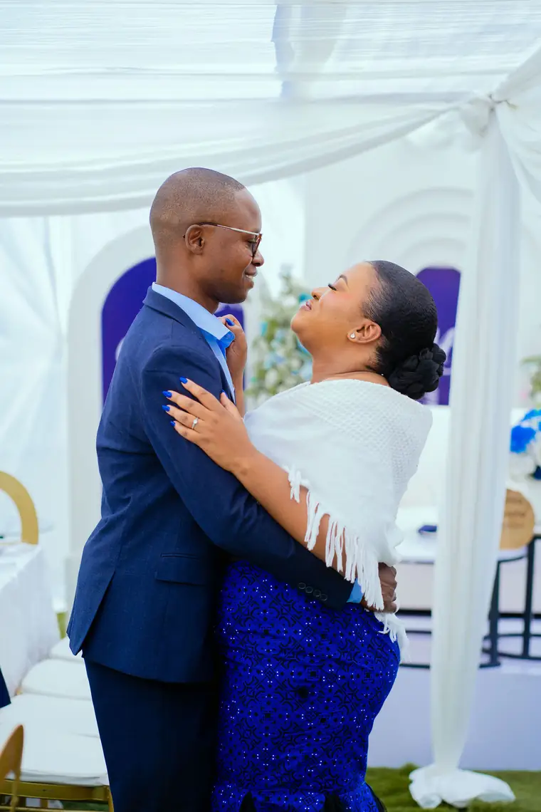 A couple in blue share a kiss under white drapes