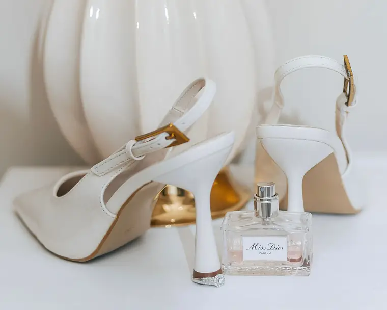 Bridal heels and perfume laid out on a white table