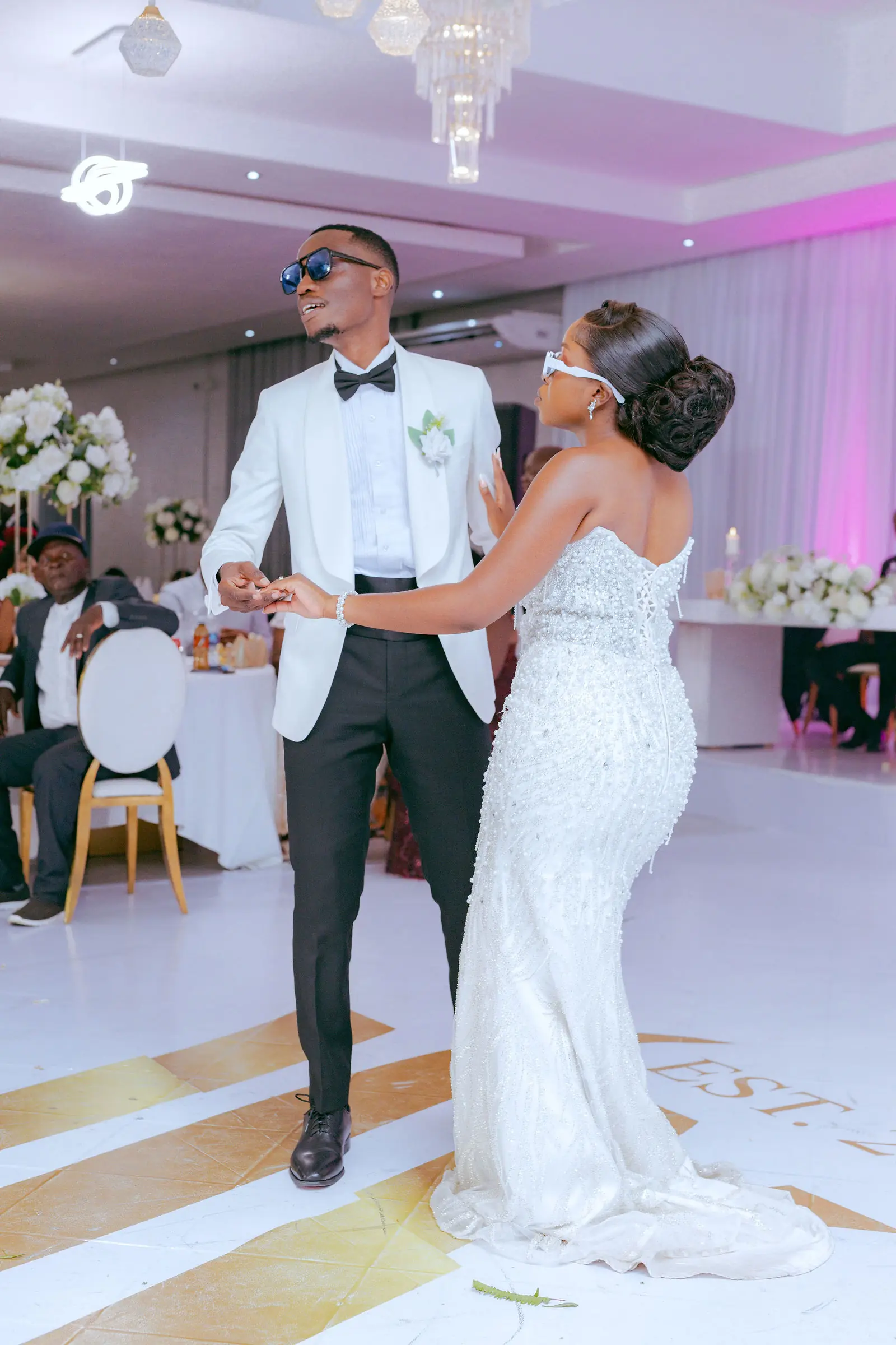 A bride and groom sharing their first dance under pink light