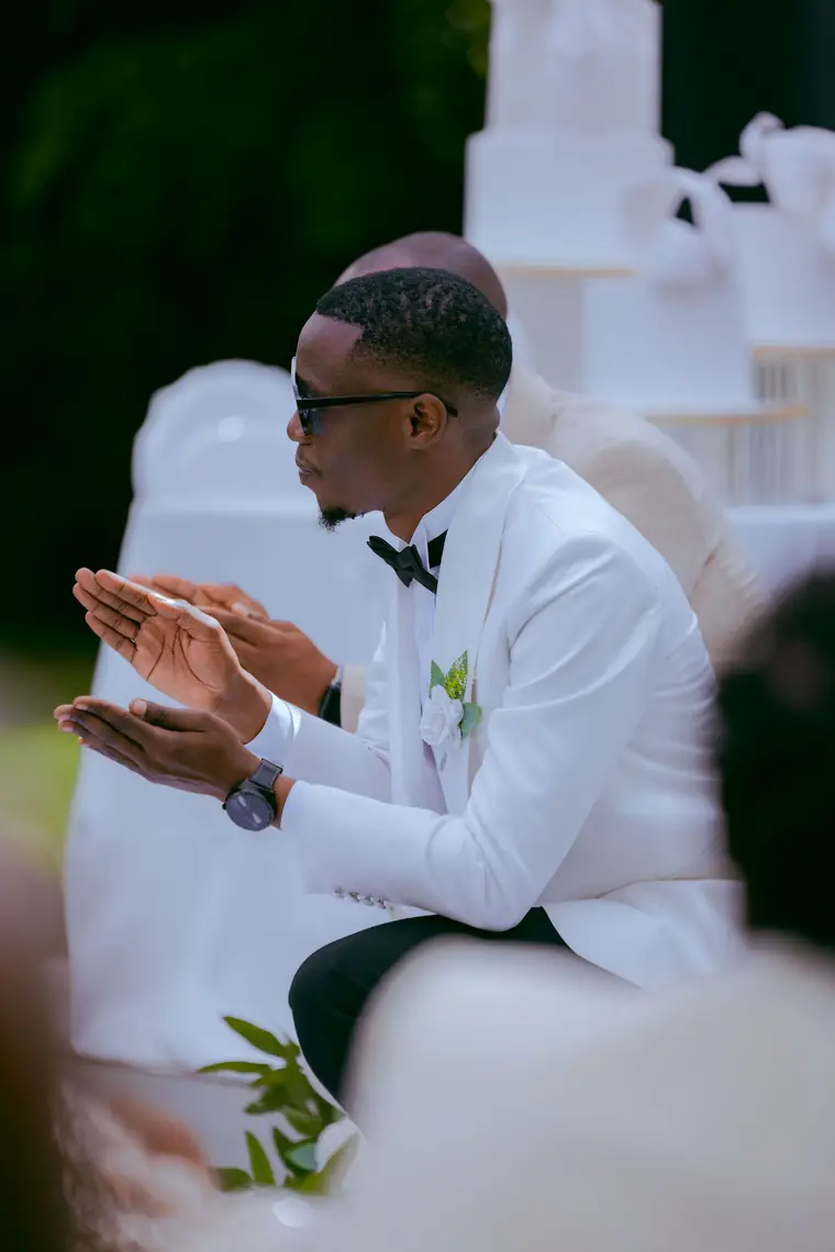 A groom clapping and smiling at his reception