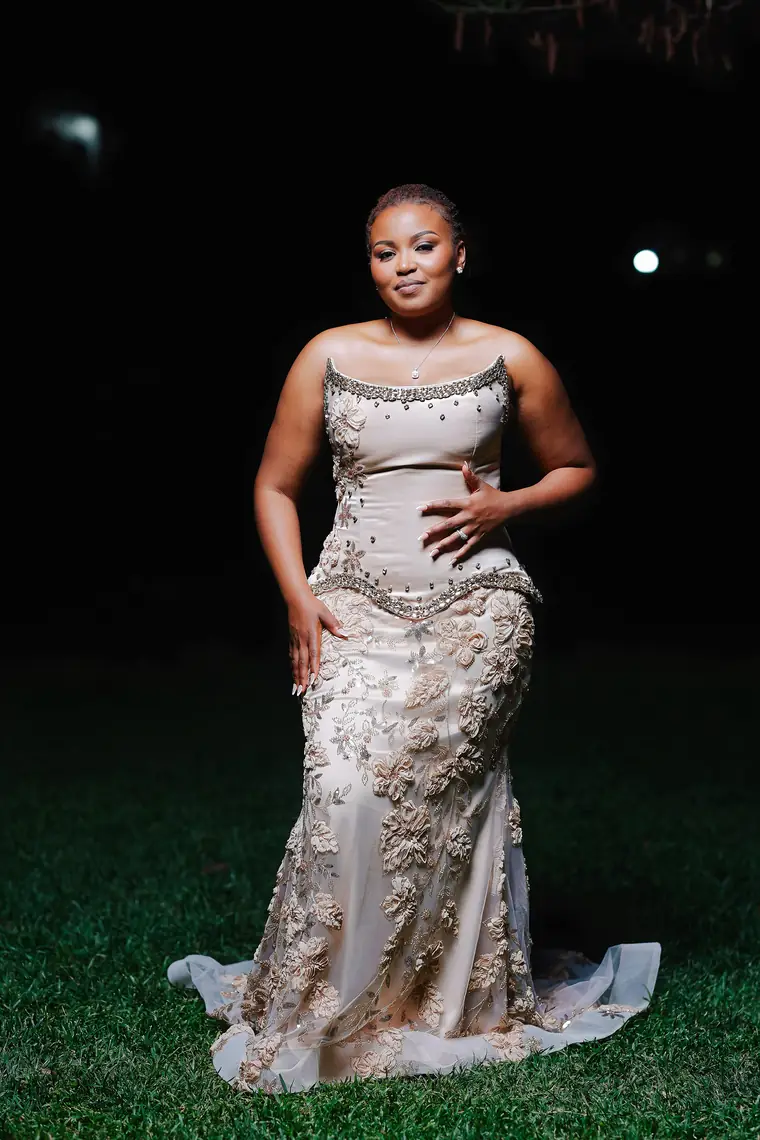 A bride in a beaded evening gown on a lawn at night
