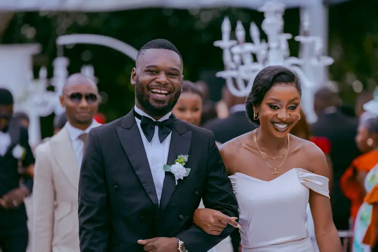 A best man and bridesmaid laughing as they walk the aisle